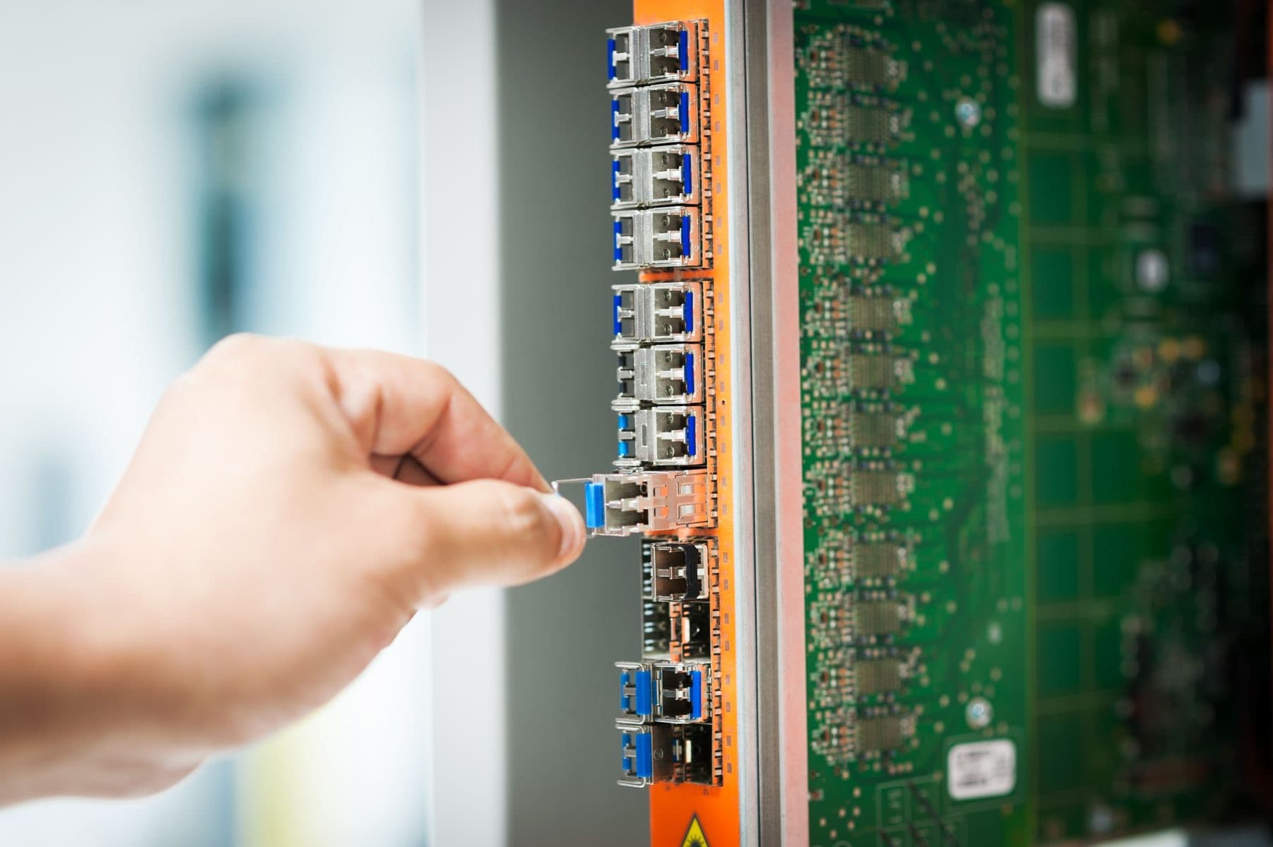 A hand connects a blue network cable to a server panel