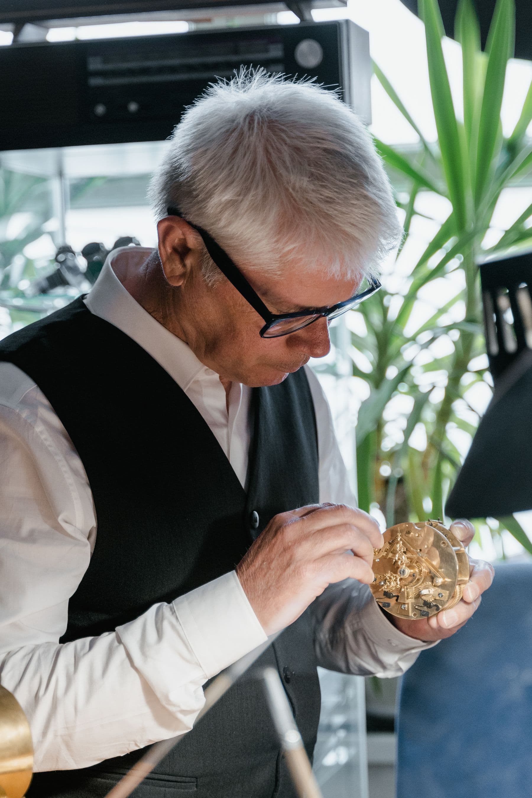 A watchmaker carefully examines a clock mechanism in his hands